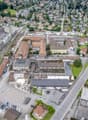 urban landscape with houses, roads, and buildings. A central area with several buildings, surrounded by other structures, including residential homes, commercial properties, and industrial facilities. Green areas, including lawns and trees, are scattered