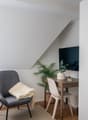 small room with bed, chair, desk, plant, and TV