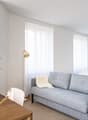 A small room with a bed, a couch, a table, a plant, and a lamp.