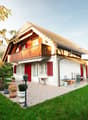white house, brown roof, red shutters, balcony, patio, garden, lawn, trees