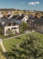New town area with several modern townhouses surrounded by greenery, paths, and a playground.