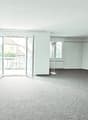 An empty room with a balcony and sliding glass doors leading to it, white walls, and a carpeted floor.