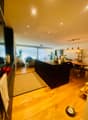 large open plan living and kitchen area, modern decor, kitchen island, dining table, living couch, wooden floor, large windows, indoor plants