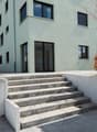 3 story building, white exterior, concrete steps, glass doors, windows, concrete walls