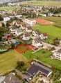 aerial view of a residential area, with various houses, solar panels, and a tennis court.