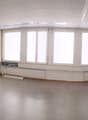 Large open office space with multiple windows, built-in shelving units, and a curved seating area along the wall.