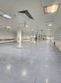 Long empty hall, white walls and ceiling, industrial style, multiple columns, windows on one side, fire extinguisher.
