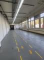 industrial warehouse, white walls, yellow painted lines on floor, tall windows, two doors on left