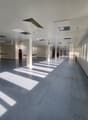 spacious room, white walls, high ceilings, gray flooring, large windows on one side, multiple red fire extinguishers