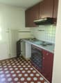 Compact kitchen with brown cabinets, white tile backsplash, stove, sink, and hexagonal tile flooring