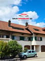 2 story house, red roof, white walls, brown shutters, 2 garages, car parked in front