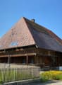 wooden traditional house, tiled roof, solar panels on roof, wooden fence, yellow flowers