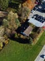 House, solar panels, multiple houses and commercial buildings in the area, grass and trees around, street with many cars parked and driving