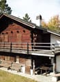 wooden chalet, wooden balcony, red brick, wooden doors, windows, outdoor table and benches, chimney