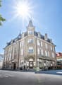 Elegant facade, multiple windows, central entrance, terrace with outdoor seating