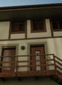 2 story house, beige and brown trim, wooden balcony, wooden doors, windows with red frames
