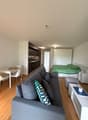 gray couch, white coffee table, white chairs, white table, green bed, pillow, nightstand, lamp, kitchen cabinets, sink, stove, oven