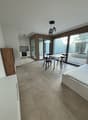 modern interior, white walls, tiled floor, white bed, white table and chairs, wooden cabinet, kitchen area with oven