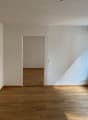 empty room, wooden floor, white walls, door, window, radiator