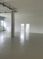 empty room, concrete floor, white walls, large windows, central column