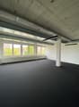 Empty room, white walls, black floor, large windows, central column