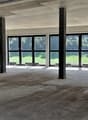 A wide empty room with many windows, two long benches, and pillars