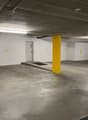 underground parking lot, white walls, yellow pillars, numbered parking spots, a black car parked in spot 27