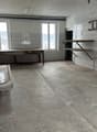 empty room, white tiles, concrete floor, wooden table, sink, ladder, 2 windows
