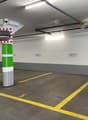 underground parking area with white walls, yellow and gray parking lines, a central pillar with a camera, a car parked
