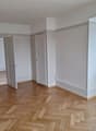 empty room, wooden parquet floor, white walls, open door, radiator, windows