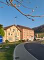 commercial building, large windows, brown roof, blue sign, grassy area, street light, parked car, mountains in the distance