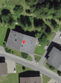 Aerial view of a neighborhood with several houses and a road, marked with a red pin.
