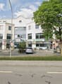 Buildings with restaurants, 2 cars parked, trees in front, road with lane markings