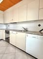 modern kitchen with white cabinets, granite countertops, dishwasher, washing machine, gas stove, wooden ceiling