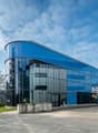 modern building with glass facade, blue panels, wide open area in front