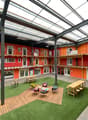 modern building with multiple levels, wooden floors, green turf, communal seating area