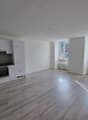 empty kitchen with white cupboards, black countertop, modern appliances, windows with a view