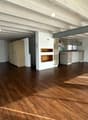 Open floor plan, wooden floors, white walls, kitchen with appliances, wooden cabinets, storage closet, hallway, bathroom