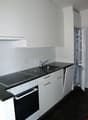 modern kitchen with white cabinets, black countertops, stainless steel sink, gas stove, oven, refrigerator, dishwasher, and a faucet
