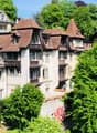 a 3 story building, white painted exterior, brown roof, balconies