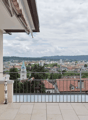 balcony with large windows, black metal railing, tiled floor, city view
