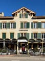 Hotel with a restaurant and tea room, red-brick facade, green shutters, a person in front of the entrance