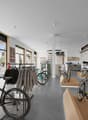 interior of a bicycle store with bikes on display, clothing racks, and large windows