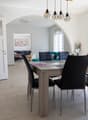 Dining room with a table and chairs, white walls, tiled floor, large windows, and a view of the outside