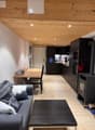 Living room with wooden floor, wooden ceiling, couch, coffee table, dining table, black fireplace