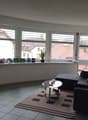 large windows, black couch, coffee table, TV, rug, potted plant