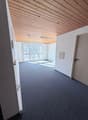 A hallway with wooden ceiling, carpet floor, large window, and white walls