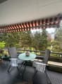 Balcony with a table, chairs, and a canopy, overlooking a grassy field and trees