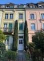 3 story house, balcony, green shutters, white door, plants and trees