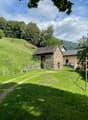 Small stone house on a slope with a balcony, located in a green landscape